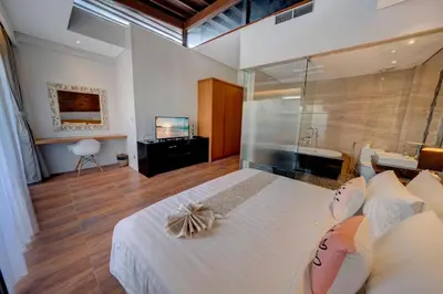 a bedroom with a large white bed and a television at Mokko Suite Villas Umalas Bali in Seminyak