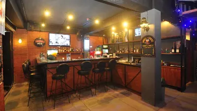 a bar with stools in a room with a television at Grand Barong Resort in Kuta
