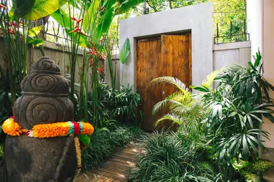 a garden with a wooden door and a statue at Villa Vickary Seminyak in Seminyak