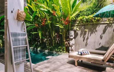 a deck with a chair and a ladder next to a pool at Villa Vickary Seminyak in Seminyak