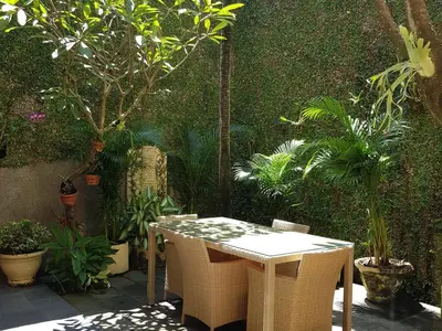 a table and chairs in a garden with plants at Villa Putu Mira By Maha Bali in Kuta