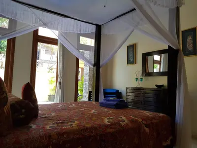 a bedroom with a canopy bed and a mirror at Villa Putu Mira By Maha Bali in Kuta