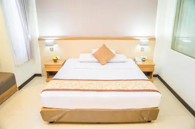 a bedroom with a large bed and two night stands at Hotel Puri Ayu in Denpasar