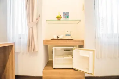 a small white refrigerator in a room with a window at Hotel Puri Ayu in Denpasar