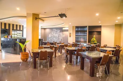 a restaurant with tables and chairs and a chandelier at Hotel Puri Ayu in Denpasar