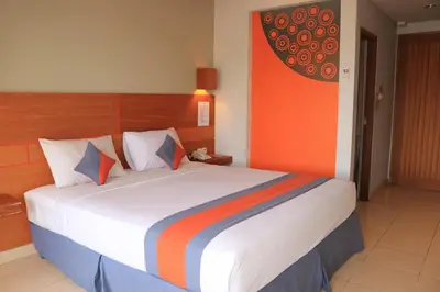 a bedroom with a large bed with an orange wall at Grand Sinar Indah in Legian