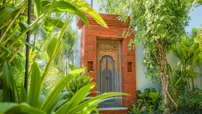 a brick house with a door in a garden at Maca Villas & Spa Bali in Seminyak