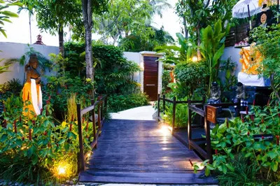 a wooden walkway leading to a house with plants at Maca Villas & Spa Bali in Seminyak