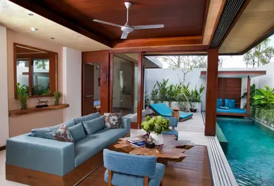 a living room with a couch and a table and a pool at Maca Villas & Spa Bali in Seminyak