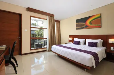 a bedroom with a bed and a desk and a window at Amadea Resort & Villas Seminyak Bali in Seminyak