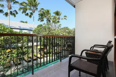 a balcony with two chairs and palm trees at Amadea Resort & Villas Seminyak Bali in Seminyak