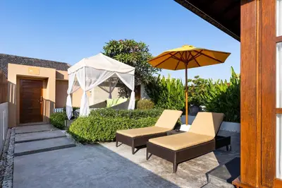 a patio with two chairs and an umbrella at Amadea Resort & Villas Seminyak Bali in Seminyak