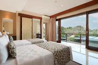 a bedroom with two beds and a large window at Amadea Resort & Villas Seminyak Bali in Seminyak