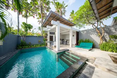 a swimming pool in a villa with a house at The Tukad Villa in Seminyak