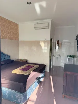 a bedroom with a large bed and a bathroom at Cempaka 2 Homestay in Legian