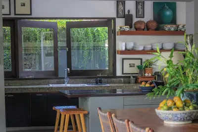 a kitchen with a sink and two windows and a table at Chimera Villas in Seminyak