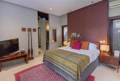 a bedroom with a large bed and a flat screen tv at Chimera Villas in Seminyak
