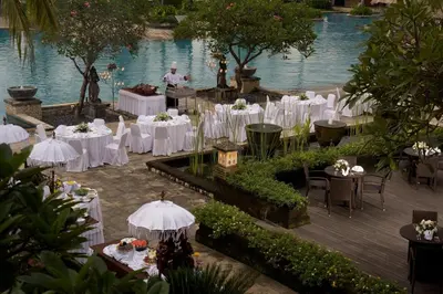 a wedding reception with white tables and chairs next to the water at The Patra Bali Resort & Villas - CHSE Certified in Kuta