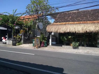 a building with a straw roof on the side of a street at Dwiputra Guest House in Canggu