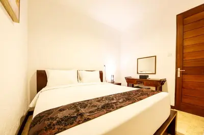 a bedroom with a large white bed and a wooden door at Villa Suzuki 1 Seminyak in Seminyak