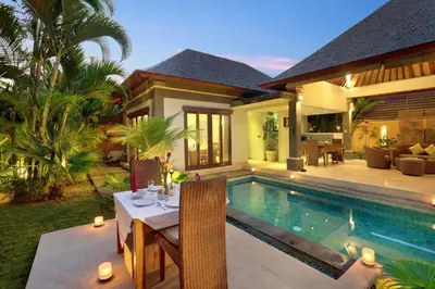 a villa with a dining table and a swimming pool at The Buah Bali Villas in Seminyak