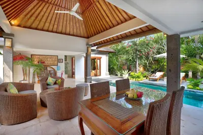 a living room with a table and chairs and a pool at The Buah Bali Villas in Seminyak