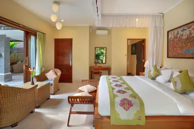 a bedroom with a large bed and a living room at The Buah Bali Villas in Seminyak