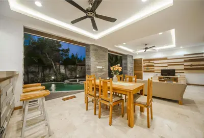 a dining room with a table and chairs and a pool at Villa Suzuki 2 Seminyak in Seminyak