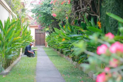 a man sitting on a bench in a garden at Heliconia Villa in Seminyak