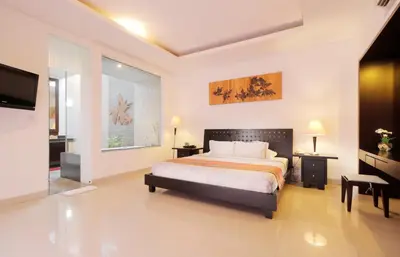 a bedroom with a bed and a television in it at Heliconia Villa in Seminyak