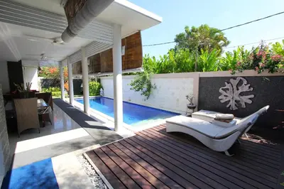 a patio with a white couch next to a swimming pool at Heliconia Villa in Seminyak