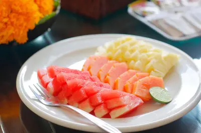 a plate of fruit on a table with a fork at Heliconia Villa in Seminyak