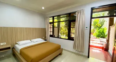 a bedroom with a bed and a large window at Simpang Inn Hotel in Legian