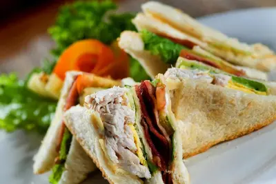a sandwich cut in half on a plate with a salad at Simpang Inn Hotel in Legian