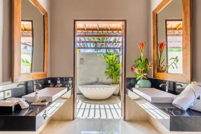 two sinks in a bathroom with two mirrors at The Akasha Seminyak Bali Luxury Villas in Seminyak