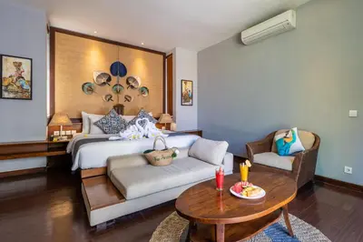 a bedroom with a bed and a table and a couch at The Akasha Seminyak Bali Luxury Villas in Seminyak