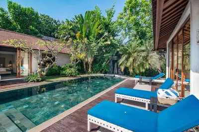 a swimming pool with blue chairs next to a house at The Akasha Seminyak Bali Luxury Villas in Seminyak