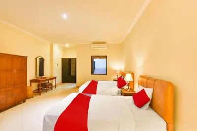 a hotel room with two beds and a desk at Super OYO Townhouse Oak Maxi Hotel Legian in Kuta