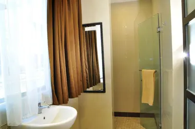 a bathroom with a sink and a shower and a mirror at Guest House Matahari in Kuta