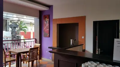 a dining room with a table and a purple wall at Guest House Matahari in Kuta
