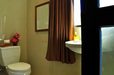 a bathroom with a toilet and a sink and a mirror at Guest House Matahari in Kuta