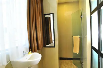 a bathroom with a sink and a glass shower at Guest House Matahari in Kuta