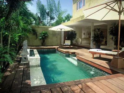 a swimming pool with a wooden deck and an umbrella at Sienna Villas Seminyak in Seminyak