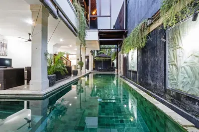 a pool in the middle of a building with green tiles at Villa Mienna in Seminyak