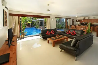 a living room with black leather furniture and a pool at Villa Blue in Seminyak