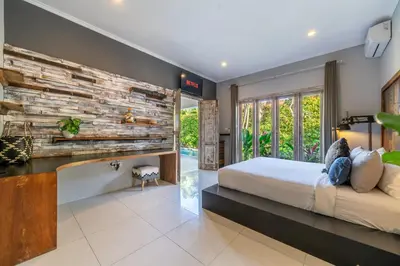a bedroom with a bed and a stone wall at Villa Sarong 1 in Seminyak