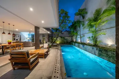 an indoor swimming pool with chairs and a table at Villa Jekumah in Seminyak
