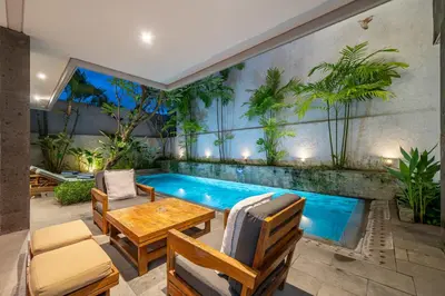a patio with a swimming pool and a table and chairs at Villa Jekumah in Seminyak