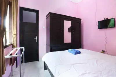 a bedroom with a white bed and pink walls at Anantaya Home Denpasar in Denpasar