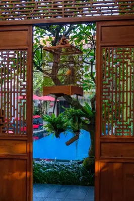 a bird cage hanging from a tree next to a pool at Kamar Kamar Boutique Hotel in Seminyak